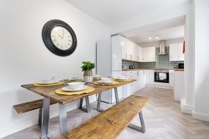 uma cozinha com uma mesa de madeira e um relógio na parede em The Valley Home - TV in every room! em Brynamman