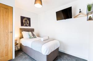 a bedroom with a bed and a flat screen tv at The Valley Home - TV in every room! in Brynamman