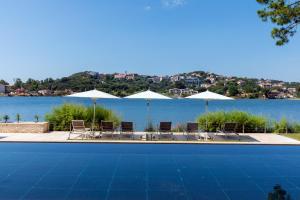a swimming pool with chairs and umbrellas next to the water at Hotel Don Cesar in Porto-Vecchio