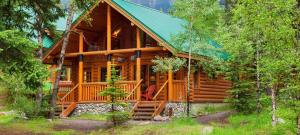 a log cabin in the woods with a green roof at Cathedral Mountain Lodge in Field