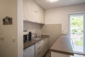 a kitchen with white cabinets and a large window at Studio Apartment Urke in Budva