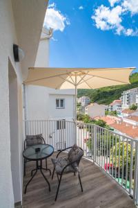 a balcony with a table and chairs and an umbrella at Studio Apartment Urke in Budva