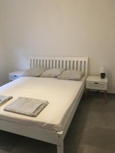 a bedroom with a white bed and a side table at Villa Dafina in Donji Štoj
