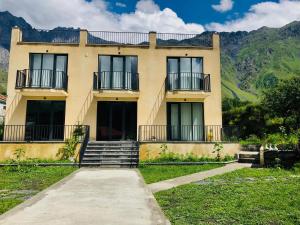 un edificio con scale e balconi di fronte alle montagne di Hotel Horizon Kazbegi a Kazbegi