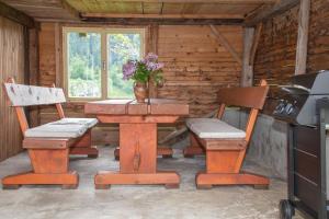 a wooden table with two chairs and a vase with flowers at Počitniška hiša Pri Goričarju in Bohinjska Bistrica