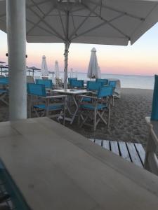 un grupo de mesas y sillas en la playa en Makedos Sea View, en Nea Vrasna