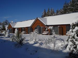 una casa cubierta de nieve delante en The Peaks Motor Inn, en Ohakune