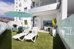 a balcony with chairs and an umbrella and a table at Oceanfront Rental in Adeje