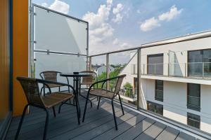 balkon z krzesłami i stołem na budynku w obiekcie Villa Nova Lux Apartment Wrocław Kowale by Noclegi Renters we Wrocławiu