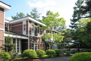 een huis met een patio en tafels en bomen bij Kyu Karuizawa Hotel Otowa No Mori in Karuizawa