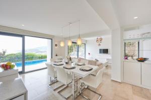 a white kitchen and dining room with a table and chairs at Luxus Villa Skyla mit 5 Schlafzimmern & Meer-Blick in Kas