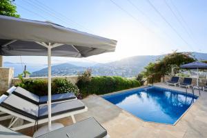 a swimming pool with two chairs and an umbrella at Luxus Villa Skyla mit 5 Schlafzimmern & Meer-Blick in Kas