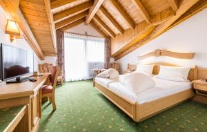 a bedroom with a bed and a desk and a television at Hotel Moserhof in Reutte