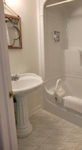 a white bathroom with a sink and a bath tub at La Maison de Sophie in Niagara on the Lake