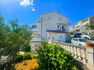 a white building with cars parked in a parking lot at Apartments Kate in Dramalj