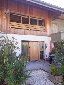 une maison avec une porte en bois et une terrasse dans l'établissement Lac et montagnes en un clin d'oeil, à Duingt
