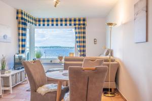 ein Wohnzimmer mit einem Tisch, Stühlen und einem Fenster in der Unterkunft fewo1846 - MeerSinne - Stilvolle Wohnung mit Balkon und Meerblick in Glücksburg