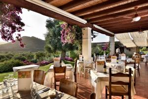 un restaurante con mesas blancas y sillas en un patio en Hotel S'Abba e Sa Murta en Tortolì