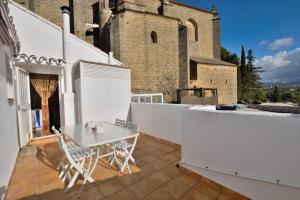 a white table and chairs on a balcony with a building at Casa del Almocabar in Ronda