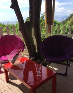 two chairs and a red table on a deck with at Les Terrasses Levantines in Île du Levant