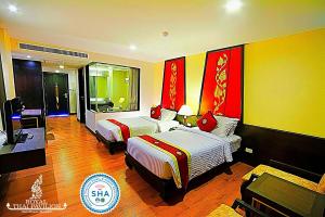 a hotel room with two beds and a television at Royal Thai Pavilion Jomtien Hotel in Jomtien Beach