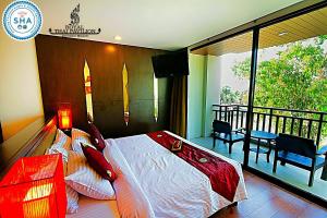 a bedroom with a large bed and a balcony at Royal Thai Pavilion Jomtien Hotel in Jomtien Beach