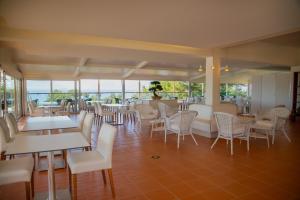 a restaurant with white chairs and tables and windows at Vila Alba Resort in Carvoeiro