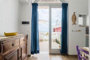 a kitchen with blue curtains and a sliding glass door at Casetta Mare in Villanova di Ostuni