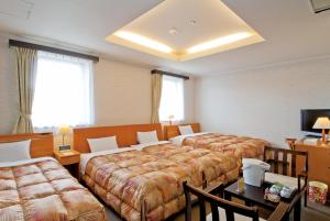 a hotel room with two beds and a table at Hotel New Ohte in Hakodate
