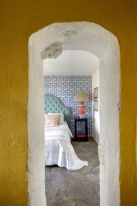 The Dutch Suite, romantic boutique guesthouse في بورتوخيلي: غرفة نوم بسرير وجدار اصفر