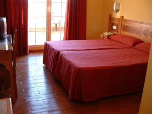 a bedroom with a large bed with a red bedspread at Villa de Gor in Gor