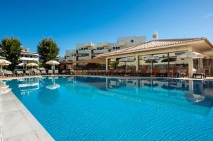 a large swimming pool in a hotel with tables and umbrellas at Oceanus Aparthotel in Albufeira
