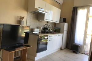 a kitchen with white cabinets and a large screen tv at Des vacances de rêve in Fréjus