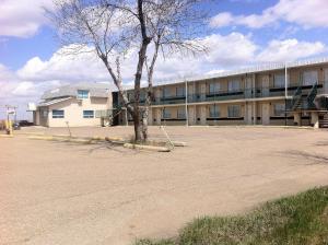 a building with a tree in the middle of a parking lot at Rainbow Motel in Swift Current