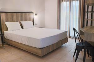 a bedroom with a large bed and a desk at Aliston Hotel Thassos in Skala Potamias