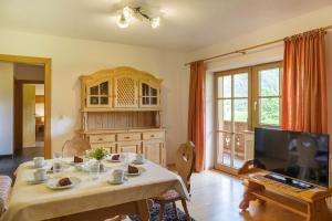 a living room with a table and a television at Landhaus Lindl - Ein ruhiges Platzl zum Wohlfühlen in Leutasch