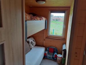 ein kleines Zimmer mit einem Etagenbett und einem Fenster in der Unterkunft Domek letniskowy Nad Stawami in Supraśl