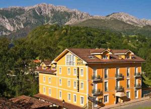 a large yellow building in front of a mountain at Hotel Picos de Europa in Arenas de Cabrales
