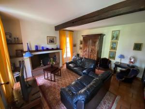 een woonkamer met een leren bank en een open haard bij La Closerie de l'Autan in Fenouillet