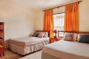 two beds in a room with orange curtains and a window at Hostel Tropical and CoWorking in San Juan del Sur