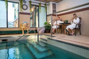 Ein Mann und eine Frau sitzen an einem Tisch neben einem Pool in der Unterkunft Clearwater Hotel Ltd in Fort McMurray