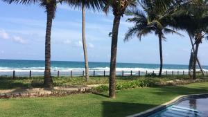 a swimming pool with palm trees and the beach at Studio Experience Marulhos Resort in Porto De Galinhas