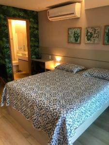 Studio Experience Marulhos Resort في بورتو دي غالينهاس: غرفة نوم بسرير لحاف ازرق وبيض