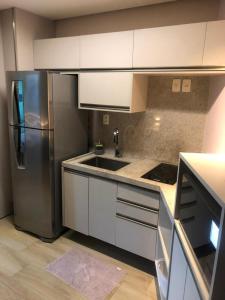 a kitchen with white cabinets and a stainless steel refrigerator at Studio Experience Marulhos Resort in Porto De Galinhas