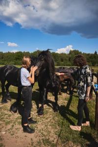 two women standing next to a black horse at Kalniaus-Sodyba in Barkellai