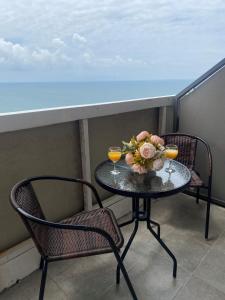 Orbi Sun&Sea Apartment في باتومي: طاولة مع كرسيين و مزهرية من الزهور على شرفة