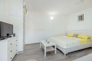 ein weißes Schlafzimmer mit einem Bett und einem TV in der Unterkunft Todorovic apartmani in Herceg-Novi