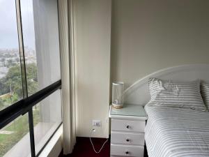 Habitación blanca con cama y ventana en Acogedor dpto en San Isidro excelente vista, piscina y wifi, en Lima