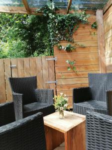 un patio con sillas de mimbre y una mesa de madera. en Puur genieten chalet met patio, bos en bosbad, en Havelte