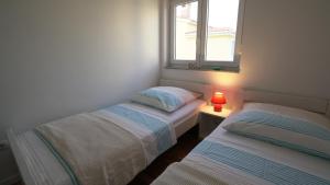 - 2 lits dans une petite chambre avec fenêtre dans l'établissement Apartment Lea - Lara, à Nin